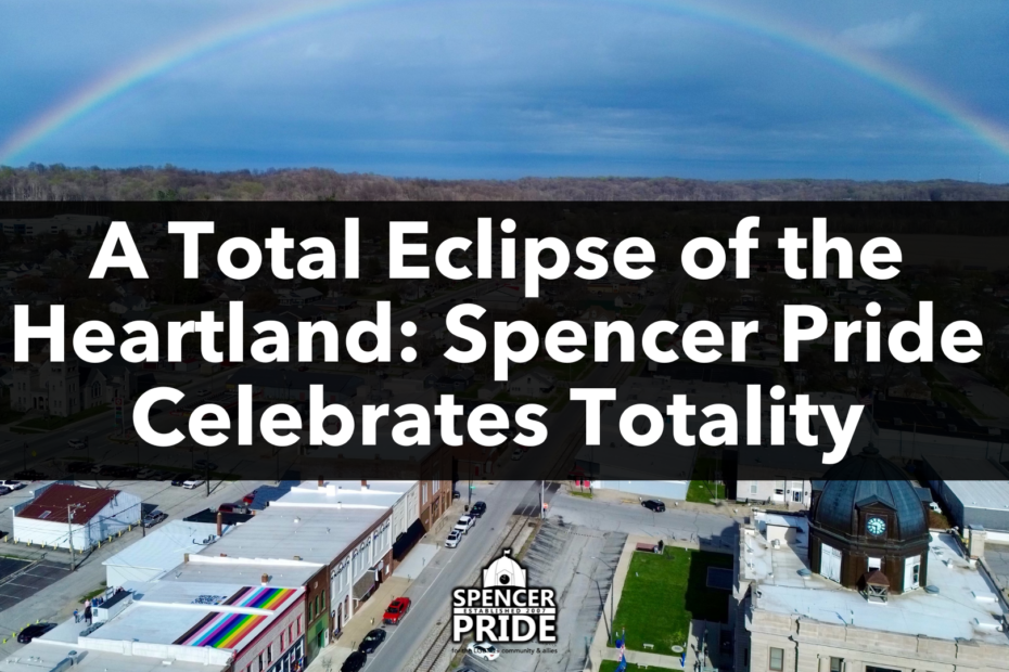 A rainbow stretches across a view of downtown Spencer, Indiana. In the foreground, the Spencer Pride commUnity center appears with a large rooftop rainbow flag.
